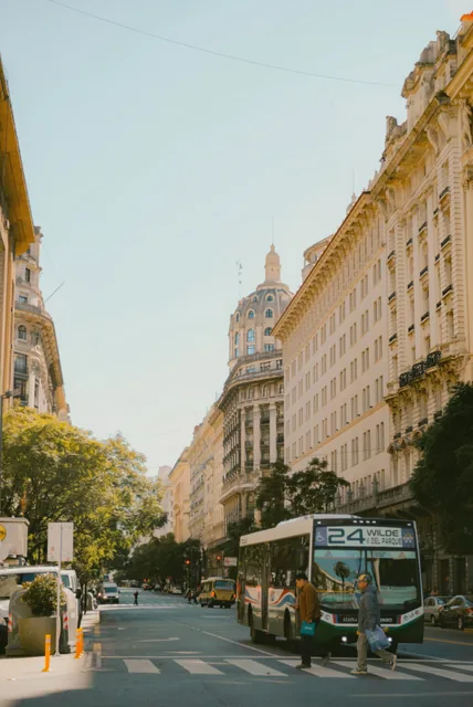A tree-lined Buenos Aires street between tall buildings with ornate facades.