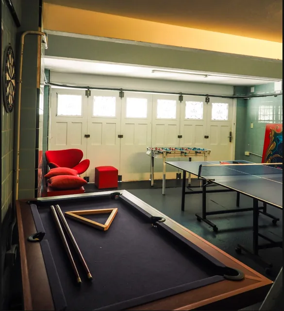 The games room with a pool table, ping pong table and red lounge chairs.