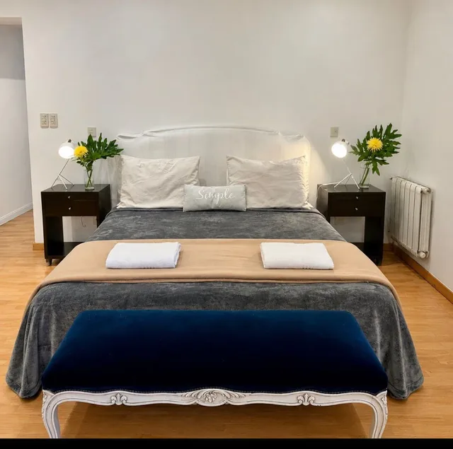 A king bed with white pillows and a navy throw in the Jacuzzi Suite.