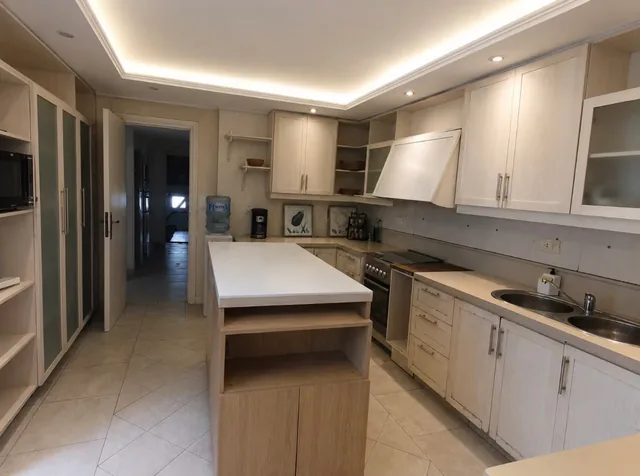The villa kitchen with white cabinets, a central island and a large cooker.