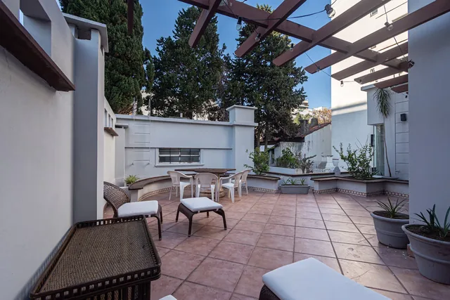 Lounge chairs on the tiled rooftop terrace beneath a wooden pergola.