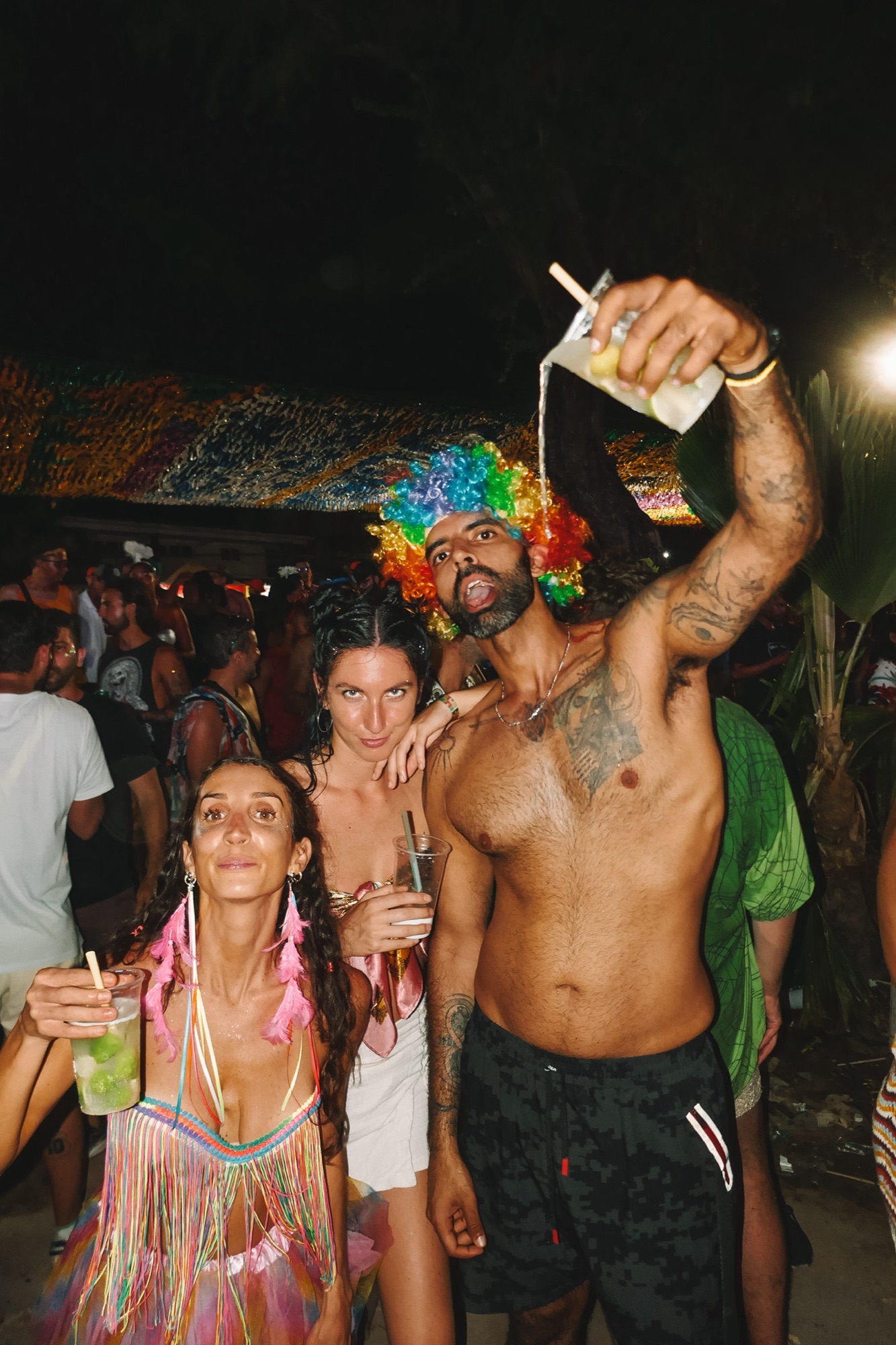 Casa Basilico guests at Carnival, one in a rainbow wig pouring a drink