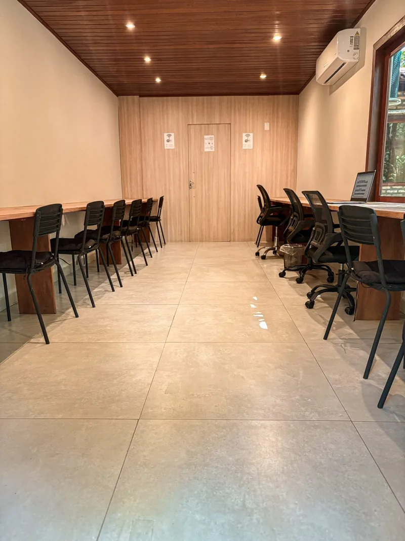 Air-conditioned common room lined with long wooden desks and office chairs for coworking