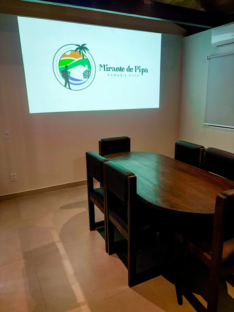 Meeting room with an oval wooden table, chairs and a wall-mounted projector screen